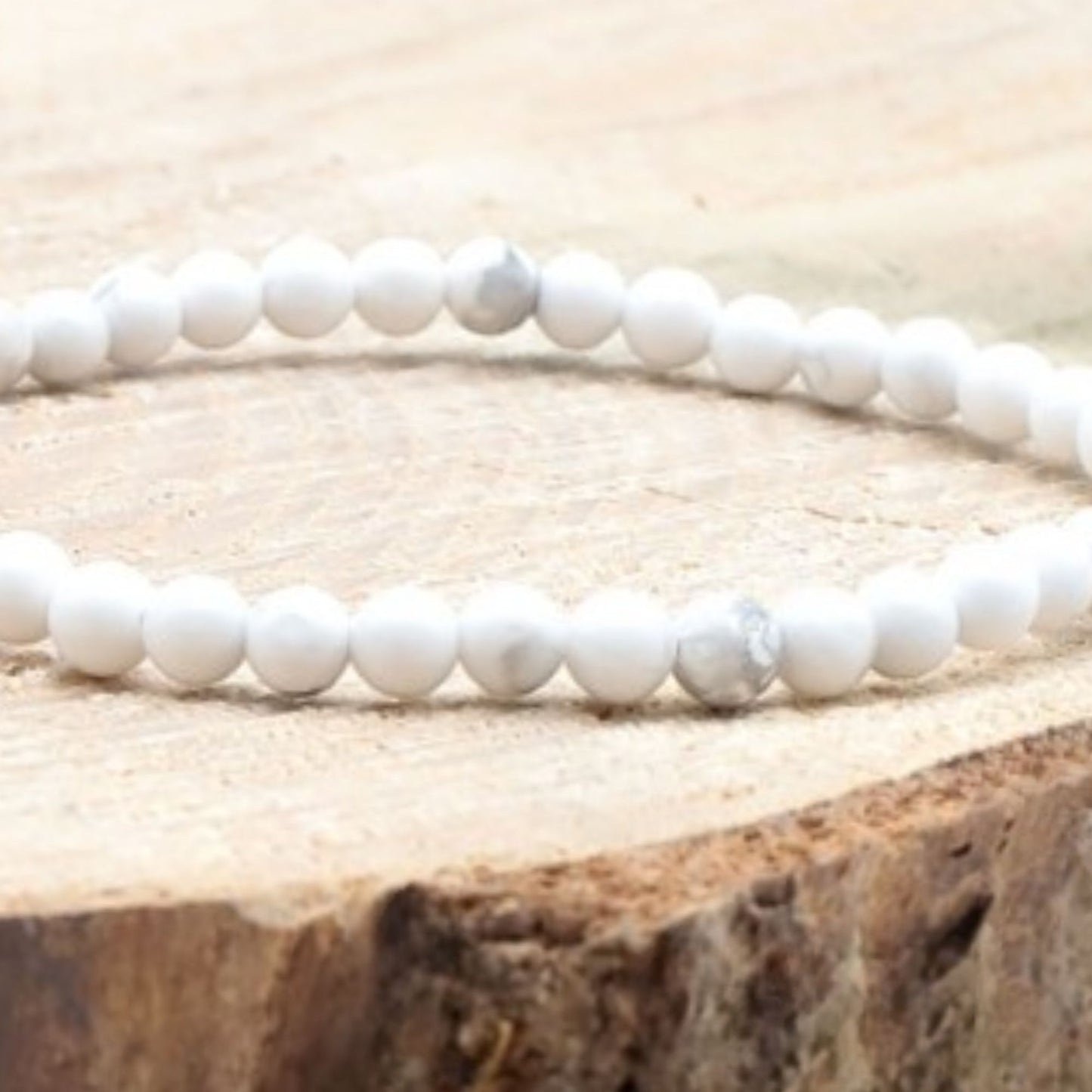 Bracelet fin en howlite blanche 4 mm présenté sur bois clair, bijou minimaliste et naturel.
