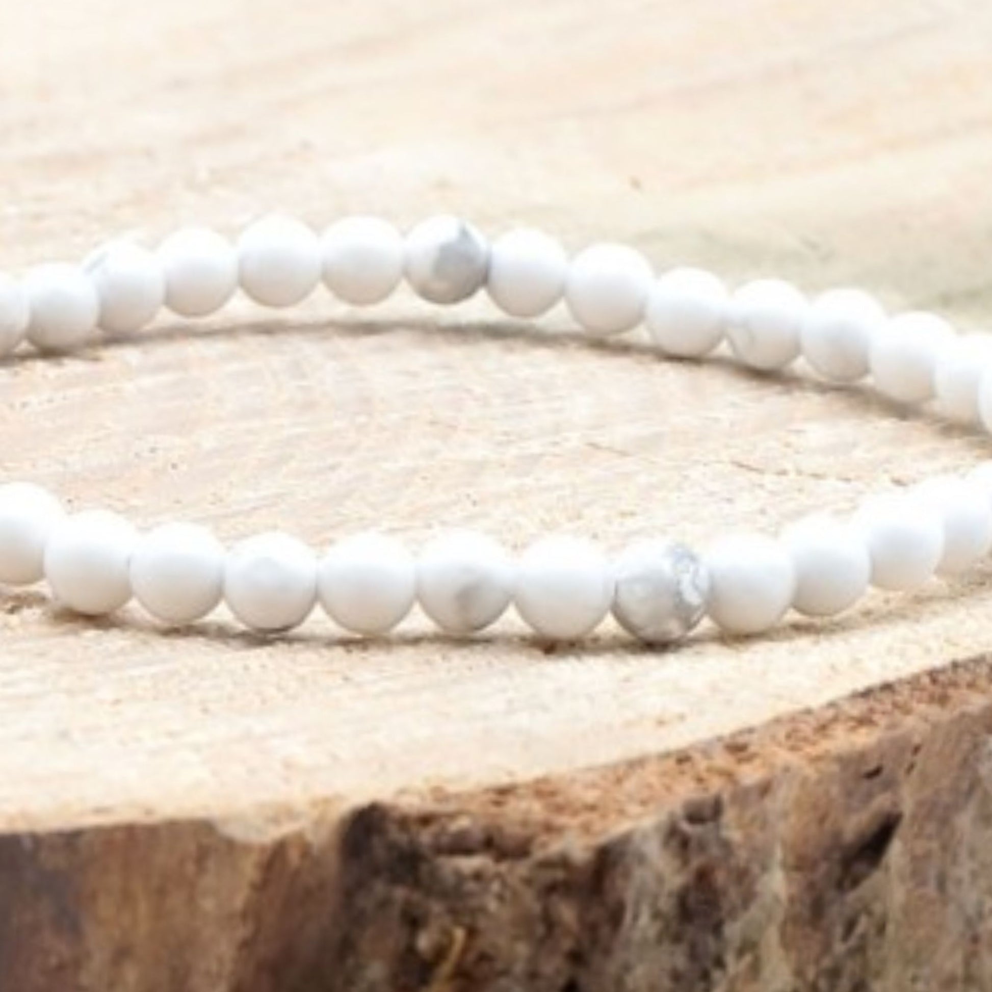 Bracelet fin en howlite blanche 4 mm présenté sur bois clair, bijou minimaliste et naturel.