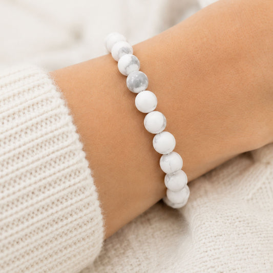 Bracelet en howlite blanche naturelle porté au poignet, perles rondes mates aux nuances grises, création artisanale YuleSens.